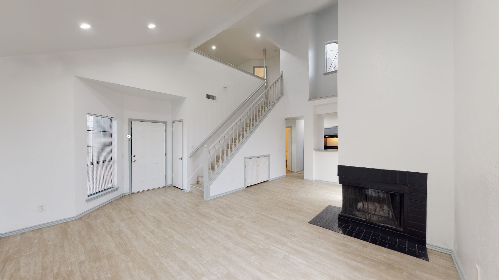 Two-story Vista Isle living room with vaulted ceiling and wood-burning fireplace